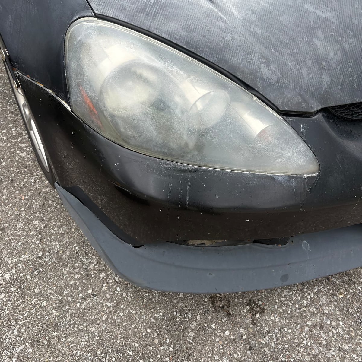 Heavily foggy oxidized headlight on a black Acura RSX before restoration