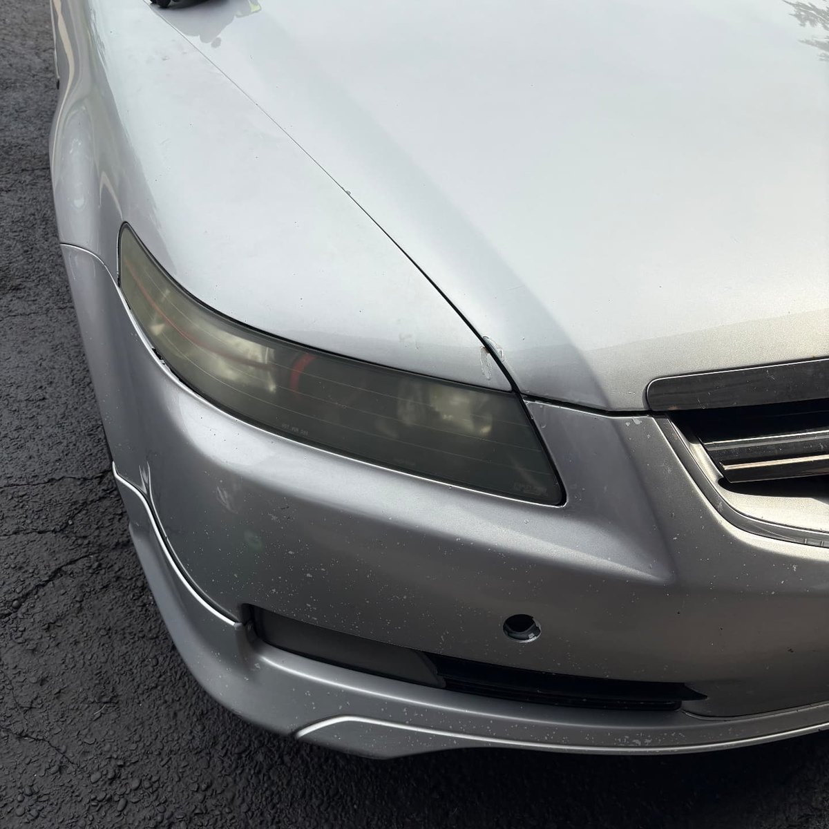 Faded yellow driver side headlight on a silver Acura TL before restoration