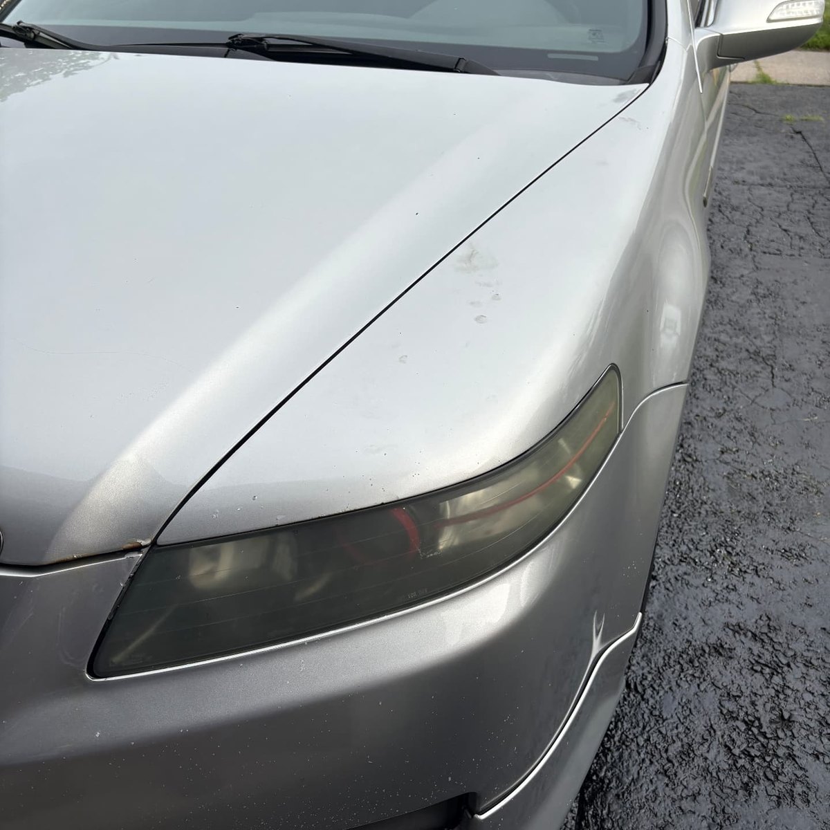 Cloudy yellow headlight lens on a silver Acura TL before restoration